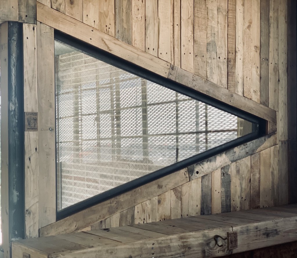 A tringle-shaped window framed and surrounded by upcycled pallet wood.