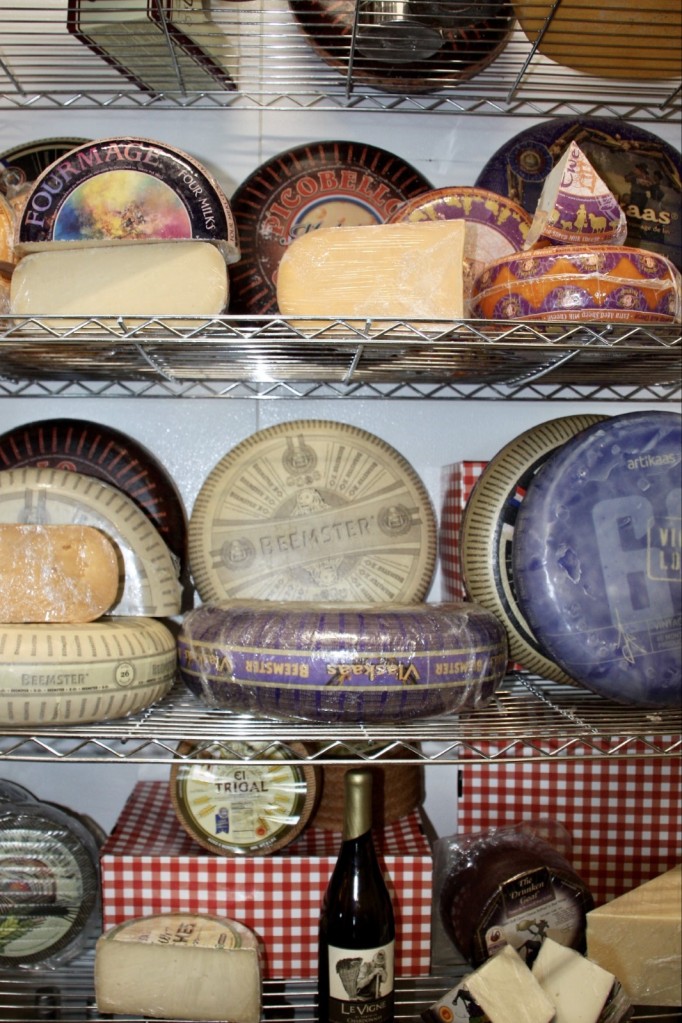 Three shelves with cheese wheels and wedges.