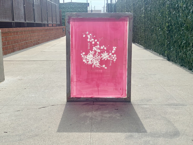 Screen printing frame with flower design on a hot pink background.